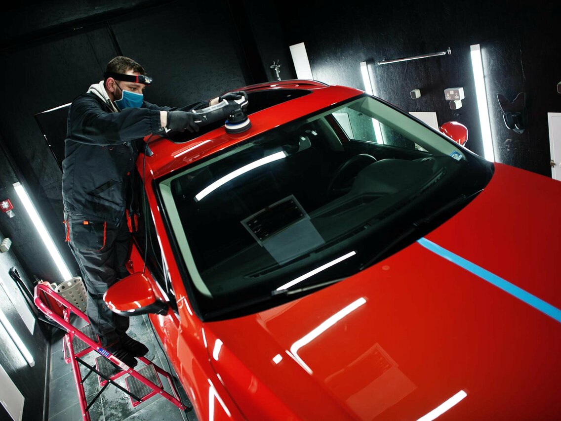 Мастер Wrap Service работает с красным автомобилем в боксе